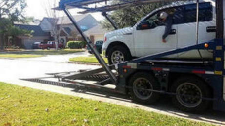 An SUV being loaded onto a car hauler.